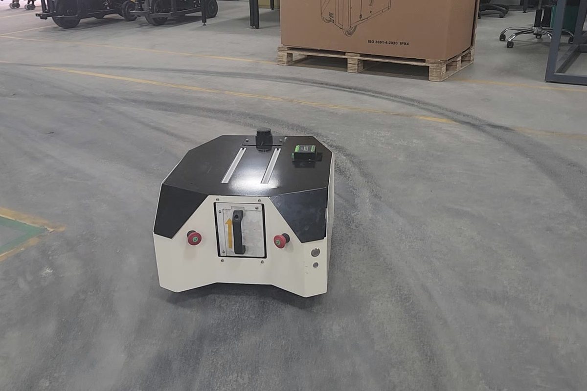 An Ati autonomous mobile robot on a plant floor, a pallet stack behind it.