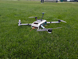 Skyfall v2, a fully enclosed white laser-sintered polyamide quadrotor, standing on grass.
