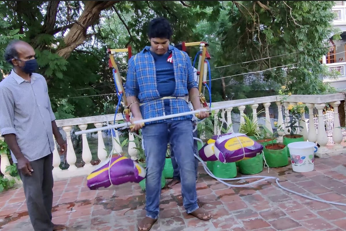 Abhiram wearing the pneumatic exoskeleton on a terrace, lifting a weighted bar.